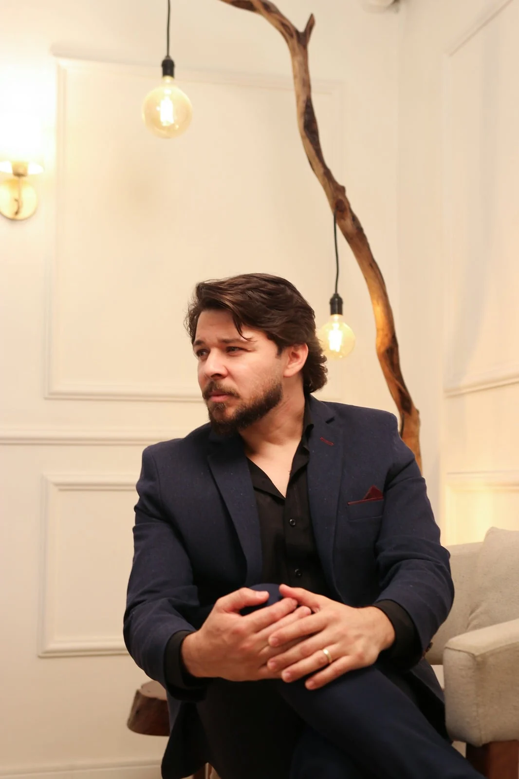 Daniel Tenorio de terno no seu estúdio, com lâmpadas Edison